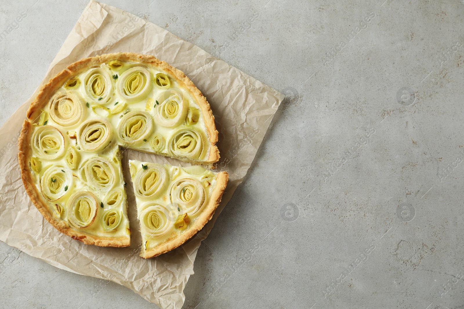 Photo of Tasty leek pie on grey textured table, top view. Space for text