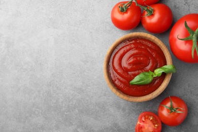 Photo of Bowl of tasty ketchup, tomatoes and basil on light grey table, flat lay. Space for text