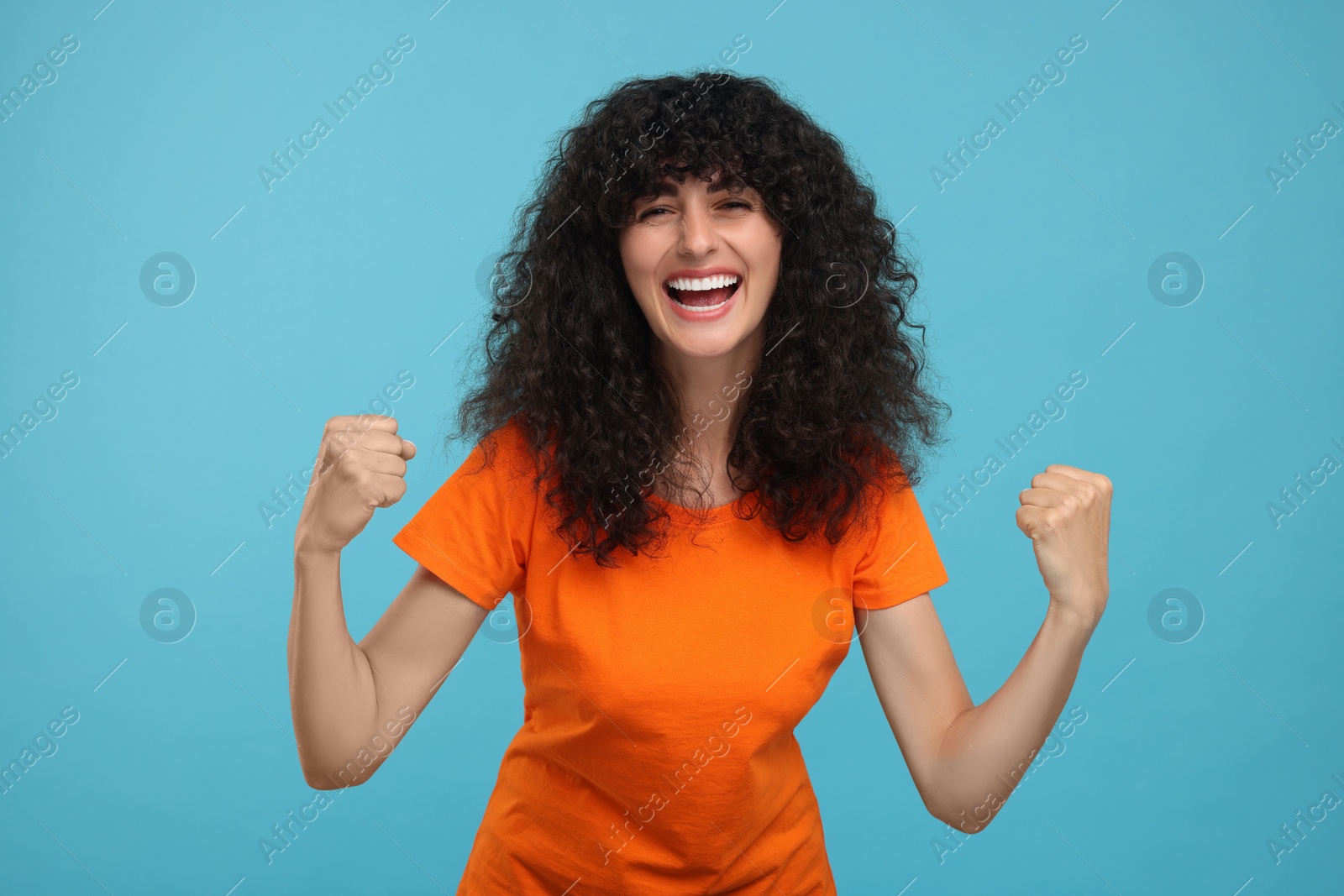 Photo of Happy sports fan celebrating on light blue background