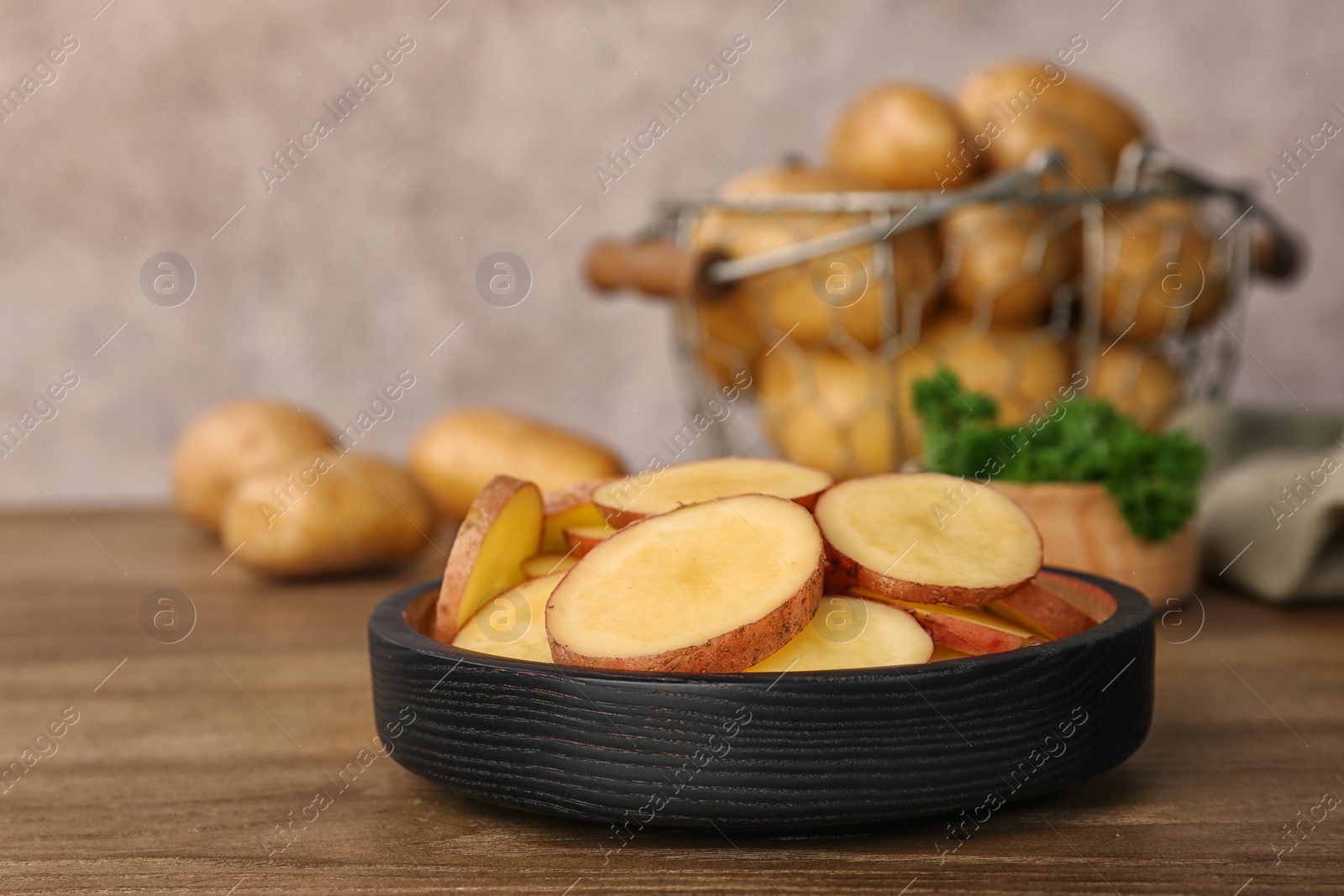 Photo of Fresh organic potatoes in dish on wooden table