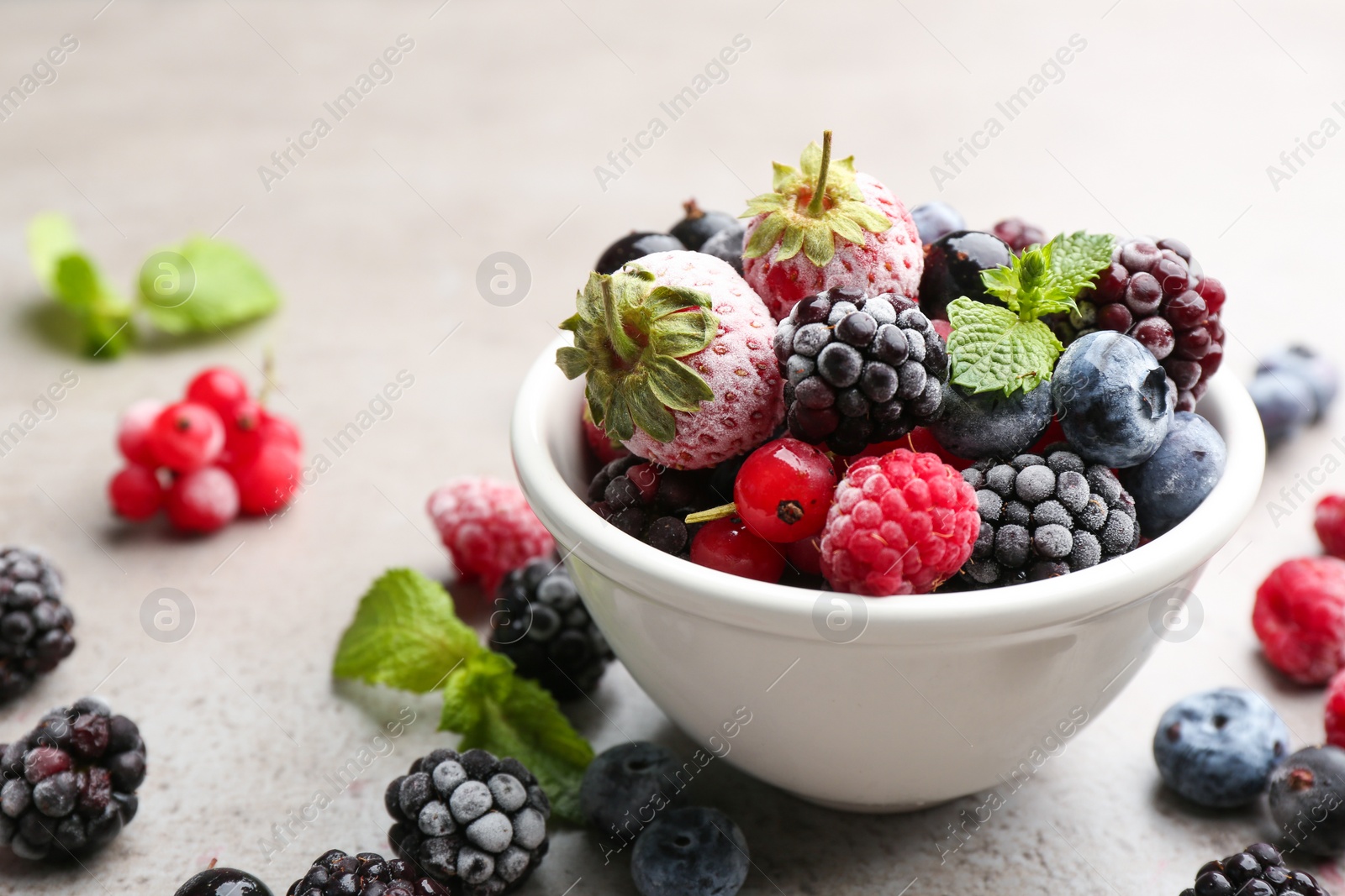 Photo of Mix of different frozen berries on grey table, closeup. Space for text