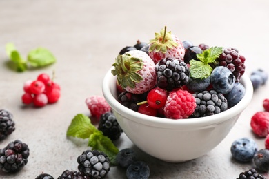 Mix of different frozen berries on grey table, closeup. Space for text