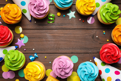 Flat lay composition with colorful birthday cupcakes on wooden table. Space for text