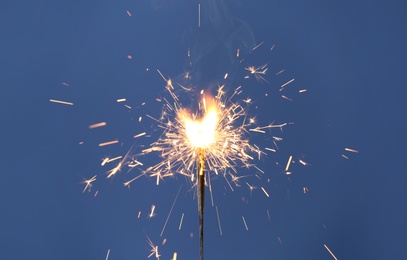 Photo of Beautiful sparklers burning on blue background. Party decor