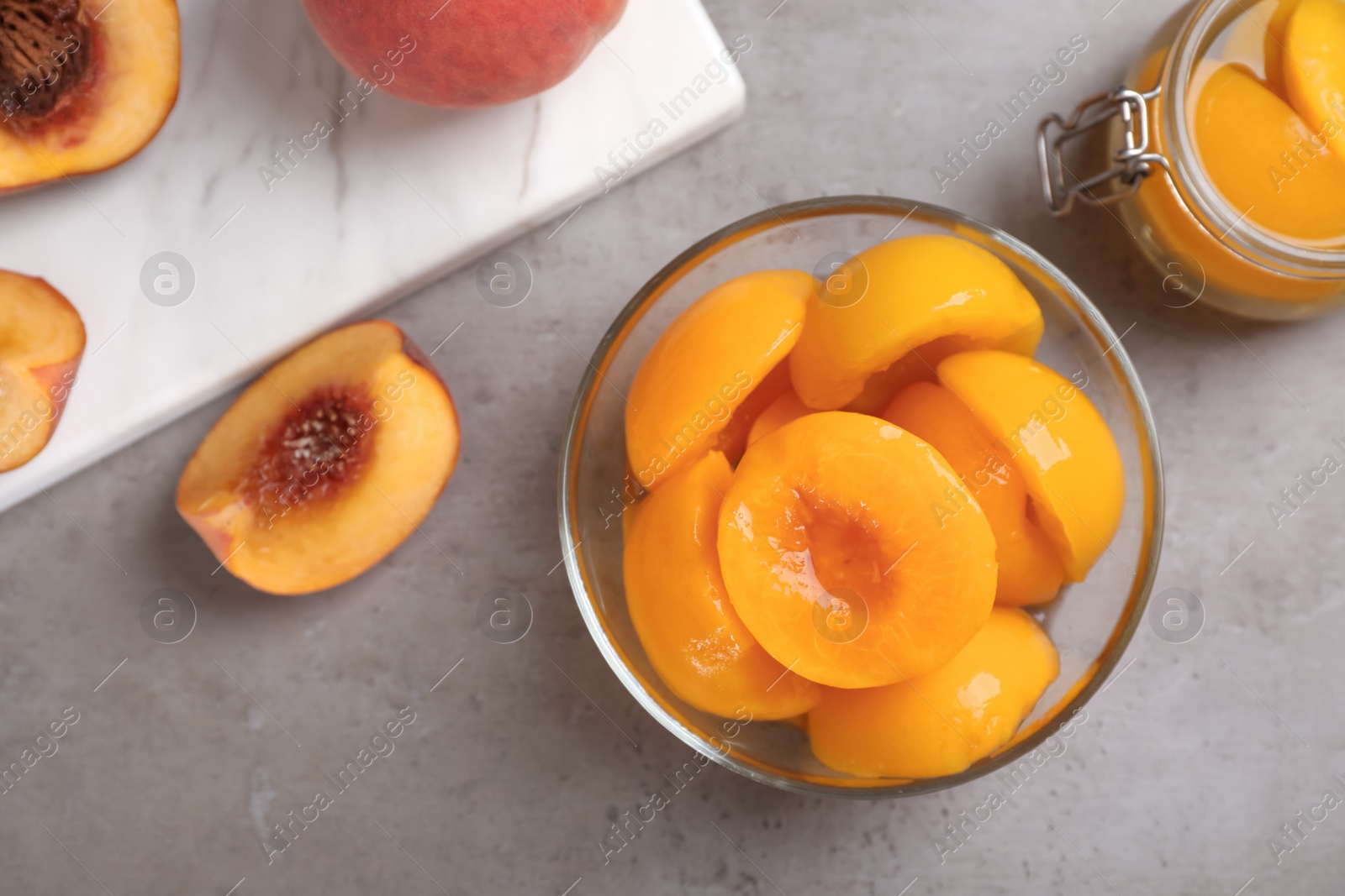 Photo of Flat lay composition with canned and fresh peaches on grey background