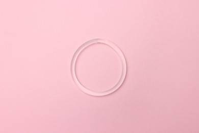 Diaphragm vaginal contraceptive ring on pink background, top view