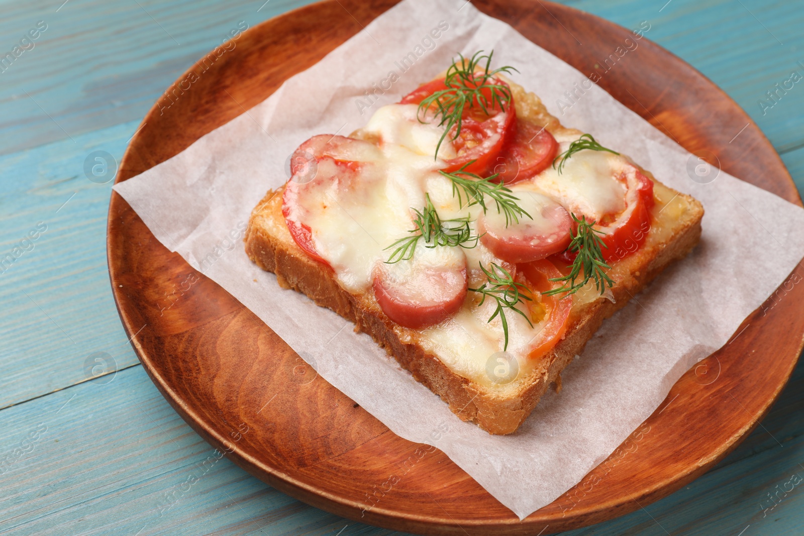 Photo of Tasty pizza toast with cheese, tomato and dill on light blue wooden table, closeup