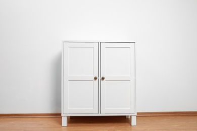 Wooden cabinet near white wall. Stylish home furniture