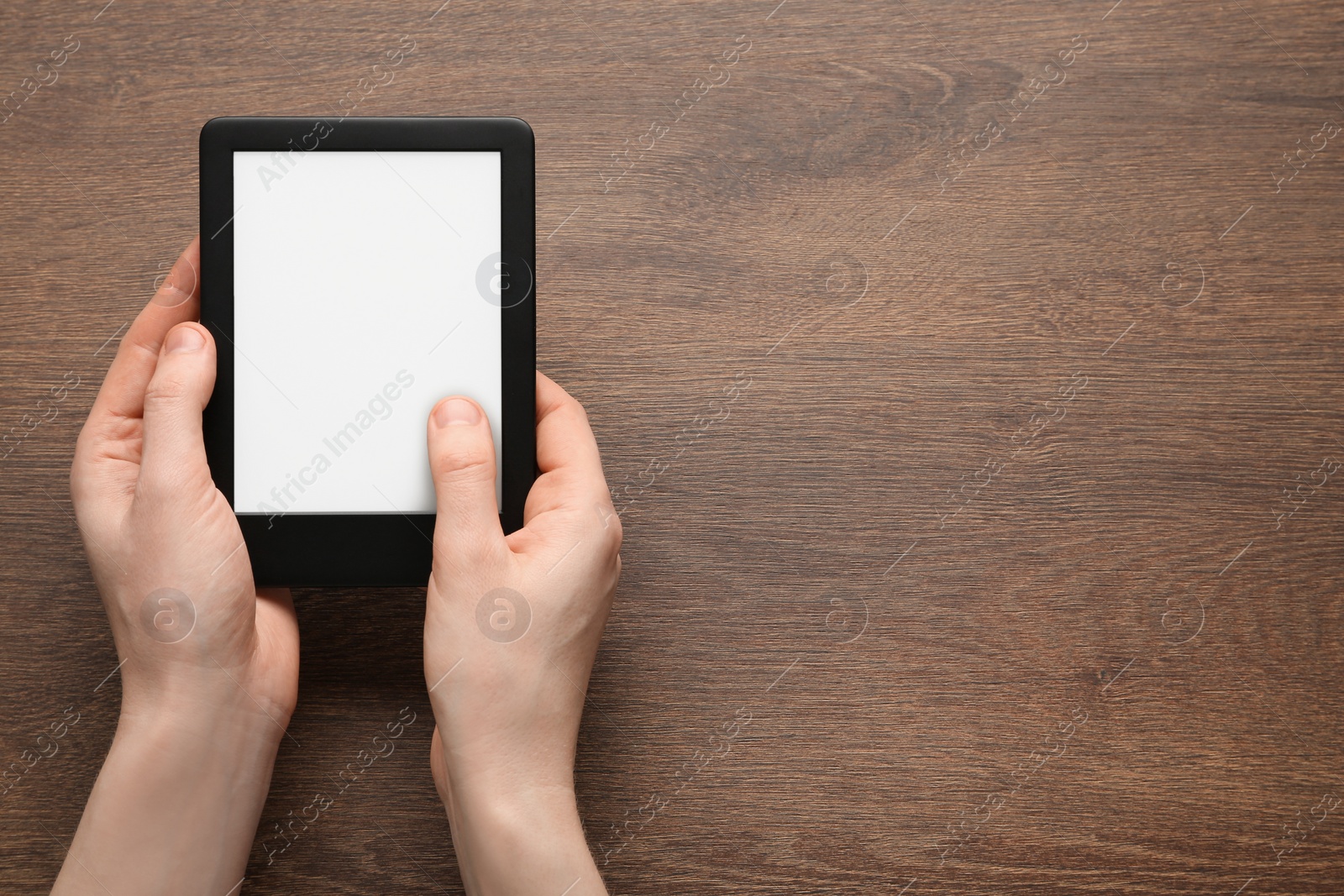 Photo of Woman using e-book reader at wooden table, top view. Space for text