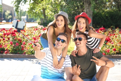 Group of young people taking selfie with monopod outdoors