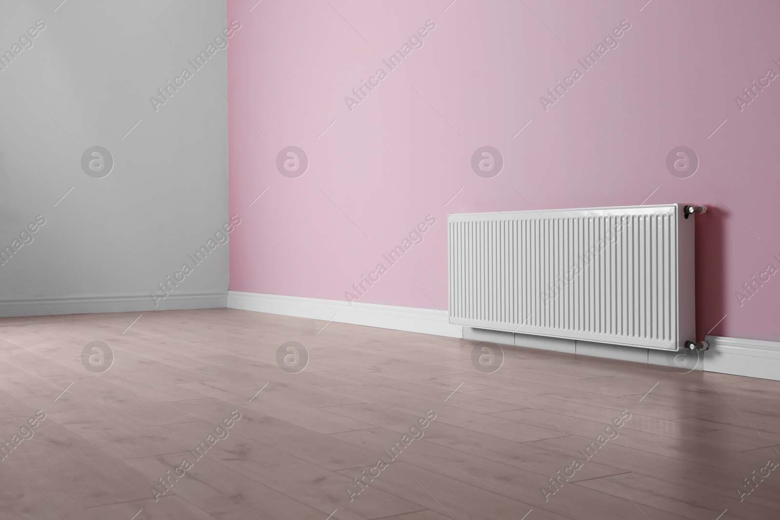 Photo of Modern radiator on color wall indoors. Central heating system