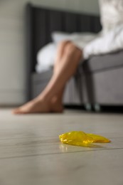 Photo of Woman sitting on bed and unrolled condom indoors, closeup. Safe sex