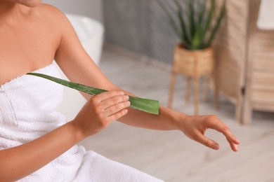 Young woman applying aloe gel onto her arm in bathroom, closeup