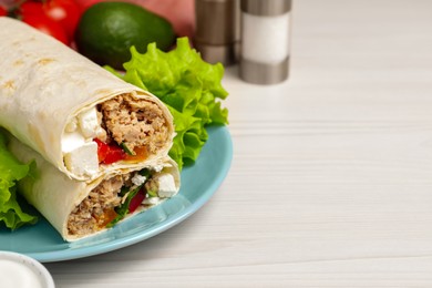 Photo of Delicious tortilla wraps with tuna on white wooden table, space for text
