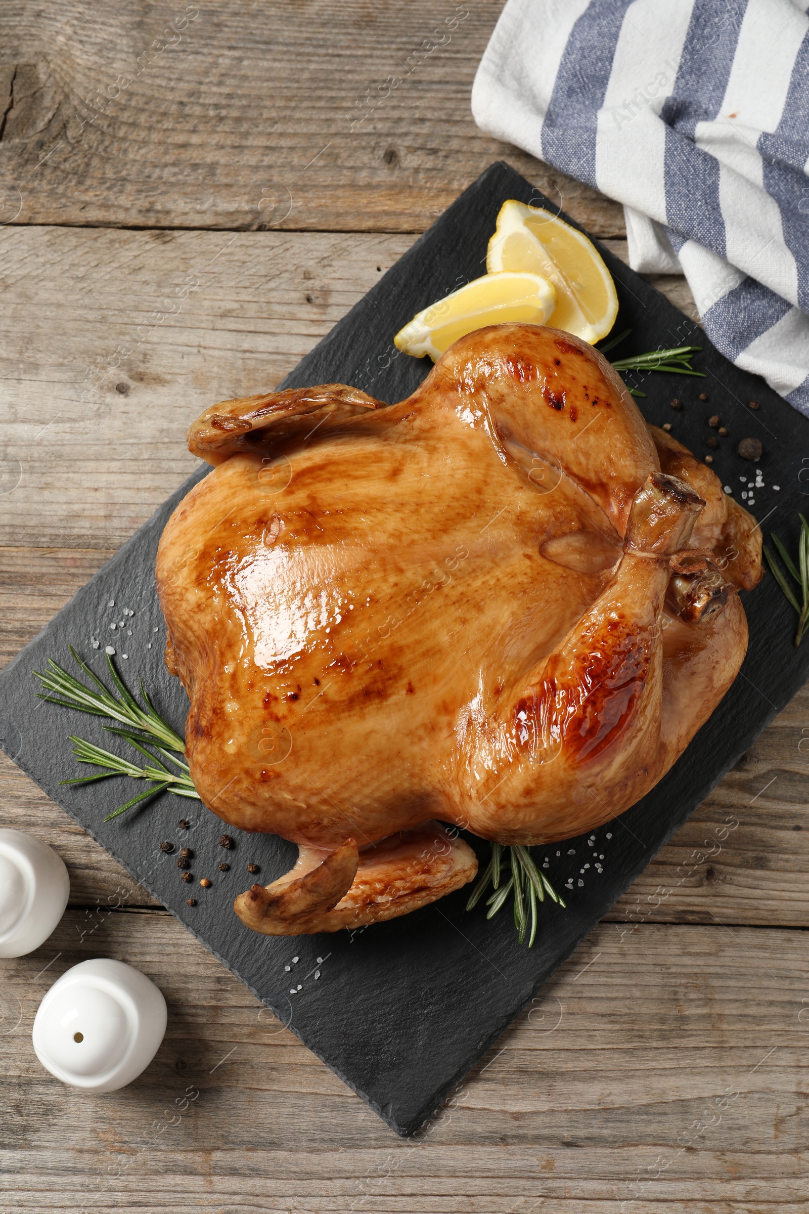 Photo of Tasty roasted chicken with spices and lemon on wooden table, top view