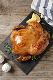 Photo of Tasty roasted chicken with spices and lemon on wooden table, top view