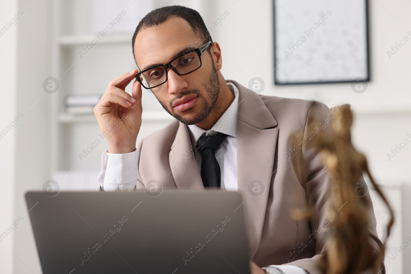 Photo of Serious lawyer working with laptop at table in office
