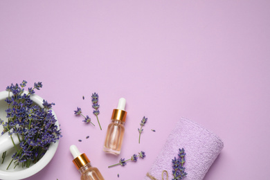 Flat lay composition with lavender flowers and natural essential oil on pink background. Space for text