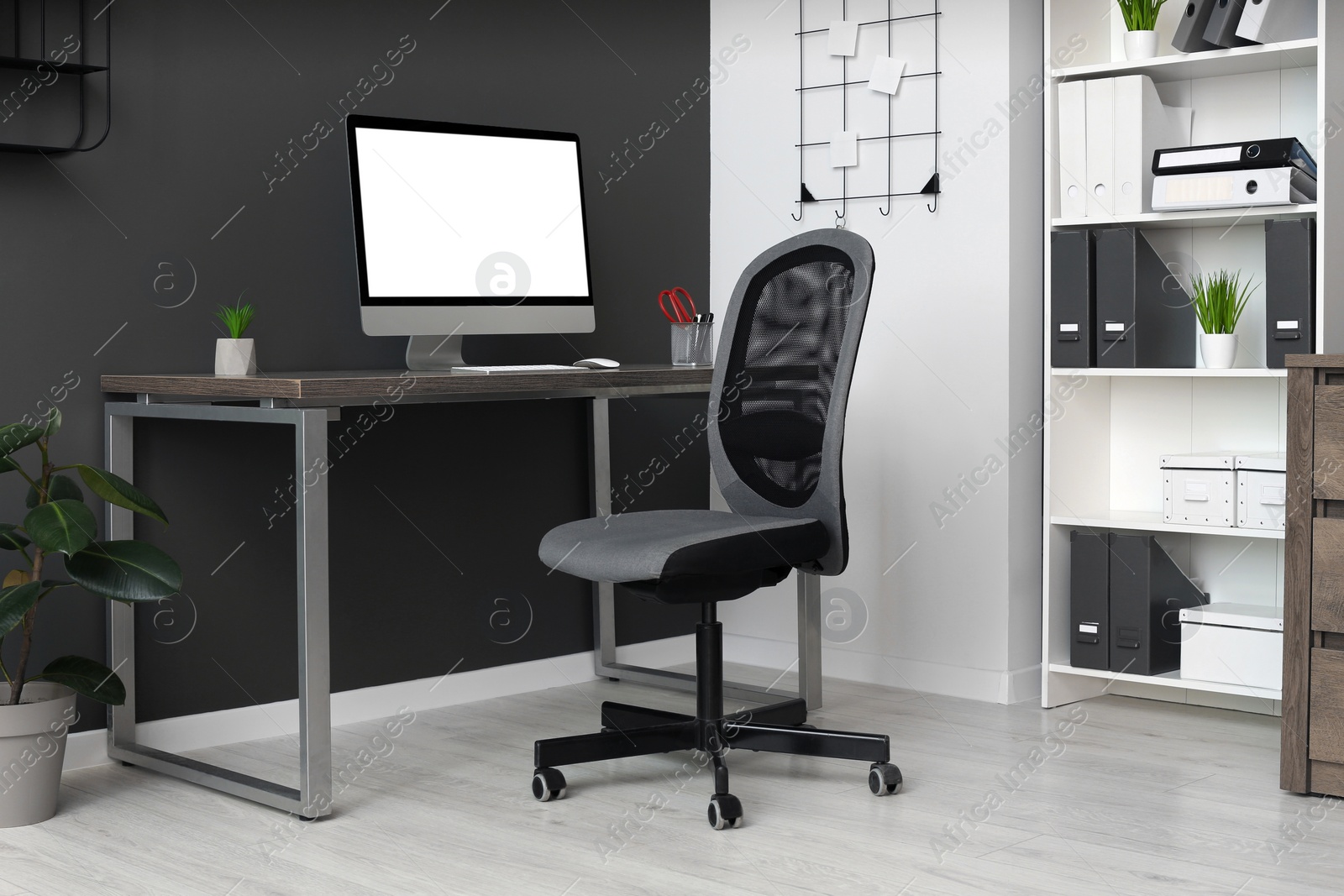 Photo of Stylish office interior with comfortable chair, desk and computer