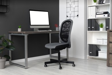 Stylish office interior with comfortable chair, desk and computer