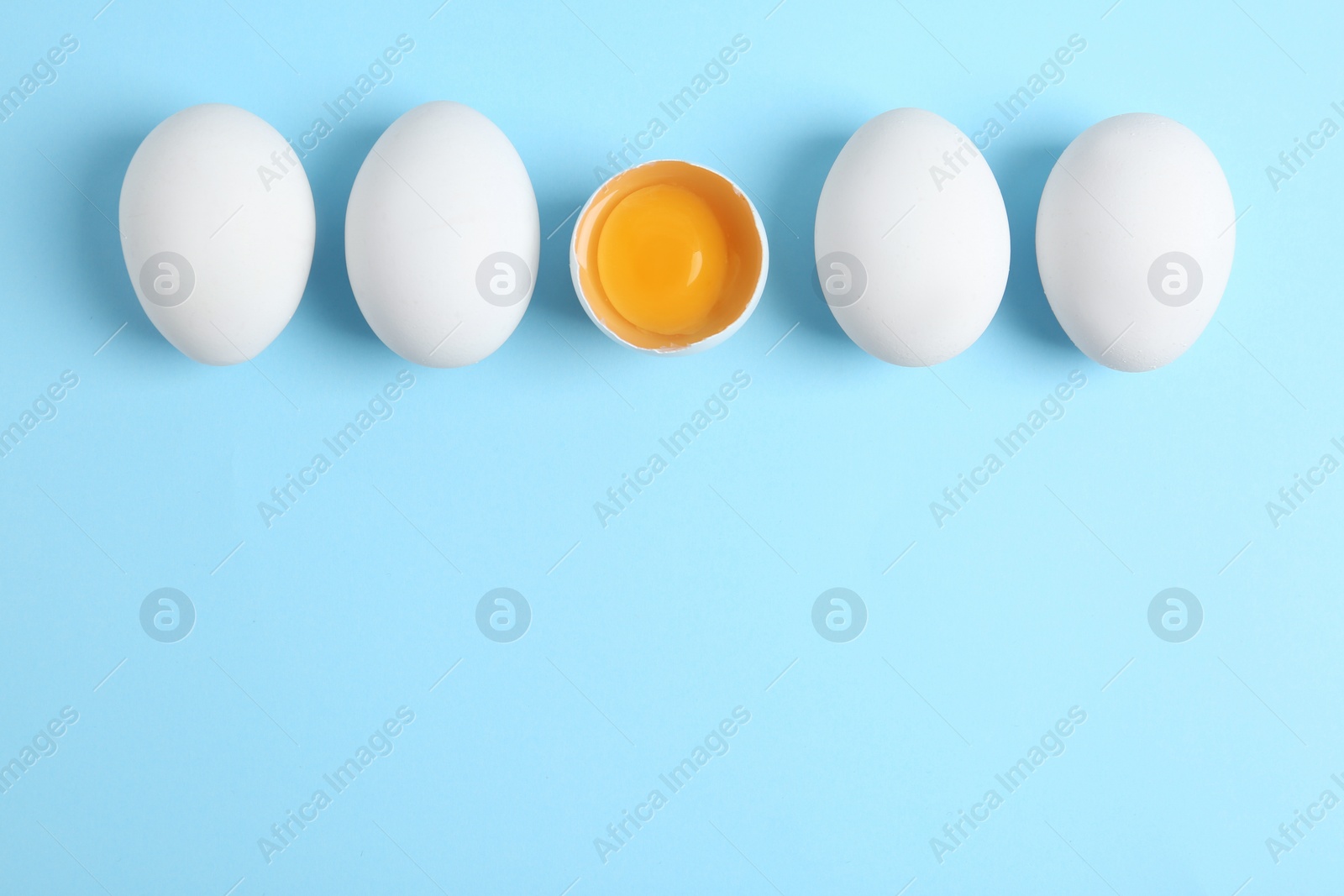 Photo of Fresh raw chicken eggs on light blue background, flat lay. Space for text