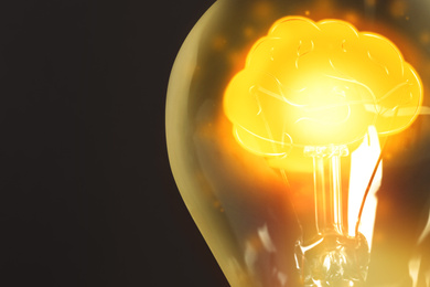 Image of Lamp bulb with shining brain inside on black background, space for text. Idea generation