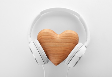 Photo of Headphones and wooden heart on white background, top view