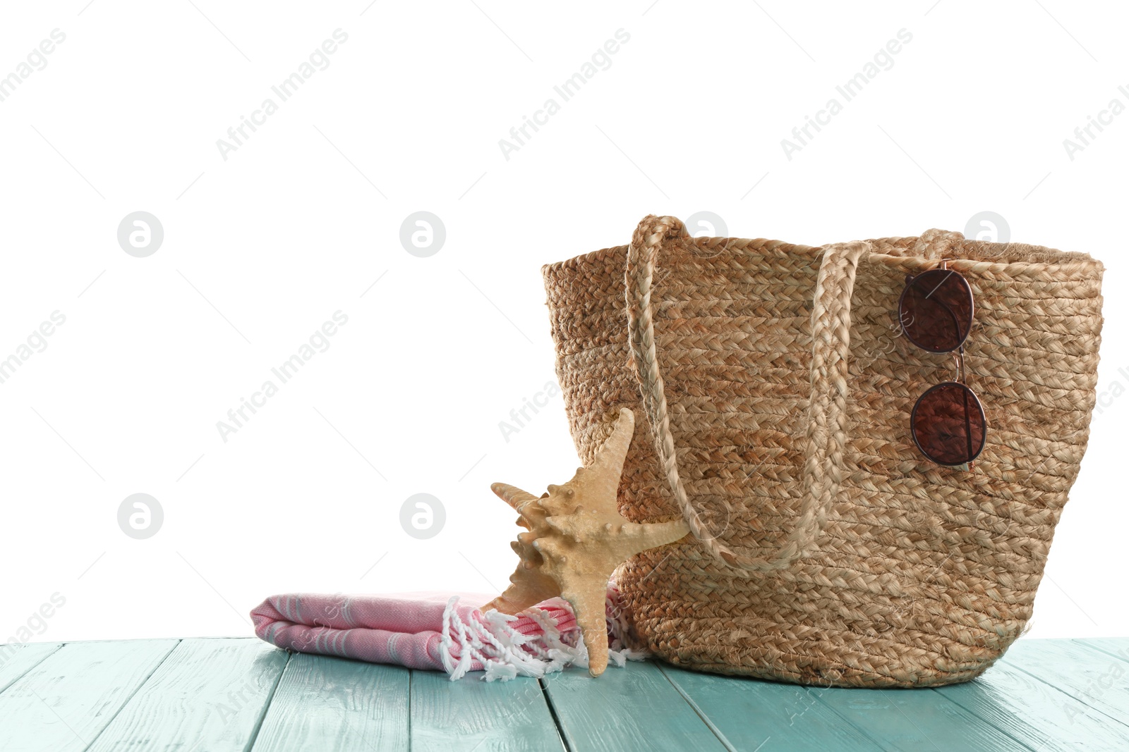 Photo of Stylish bag with beach accessories on light blue wooden table. Space for text