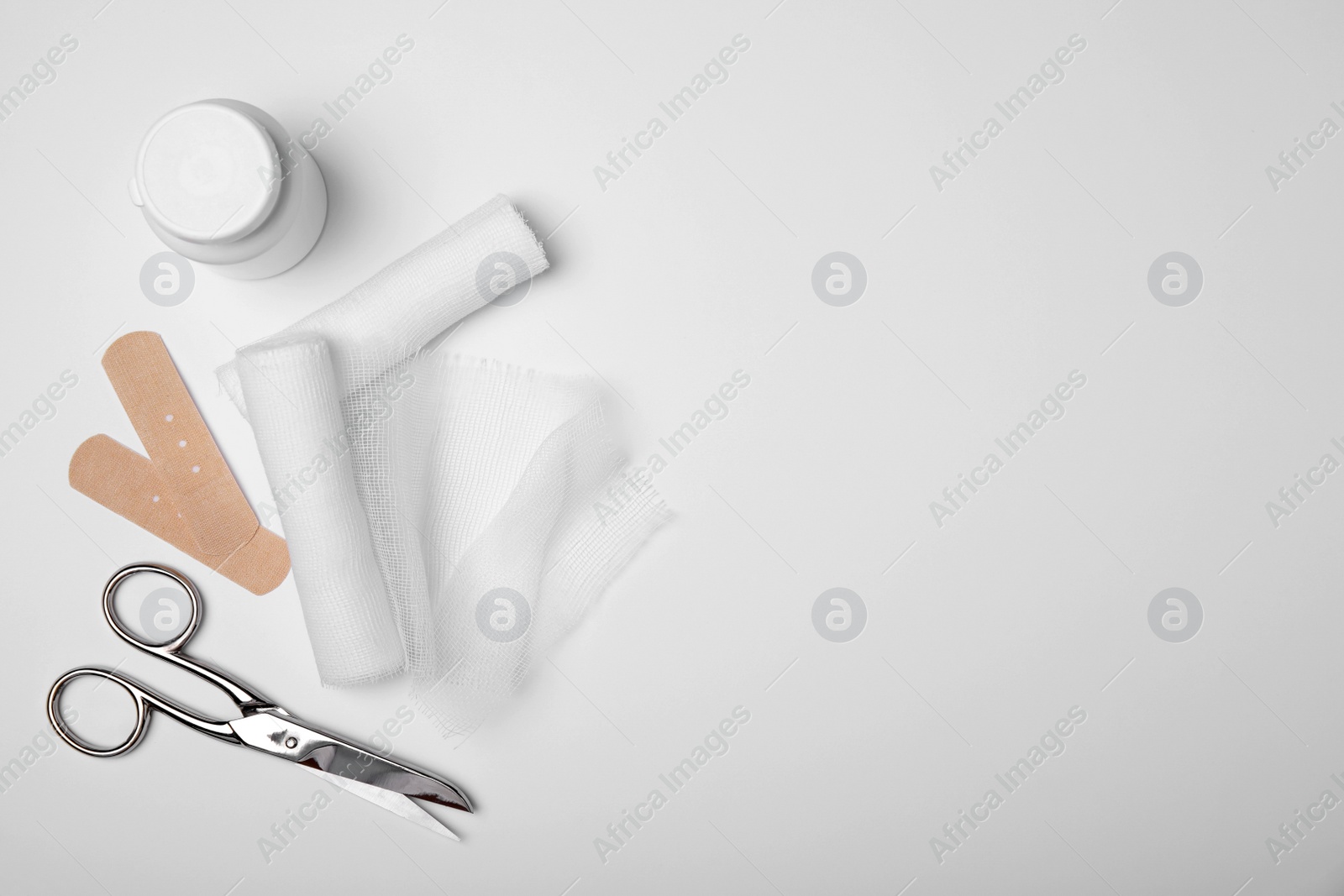 Photo of Bandage rolls and medical supplies on white background, flat lay. Space for text