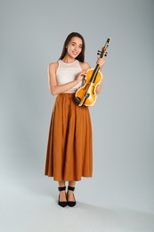 Beautiful woman with violin on grey background