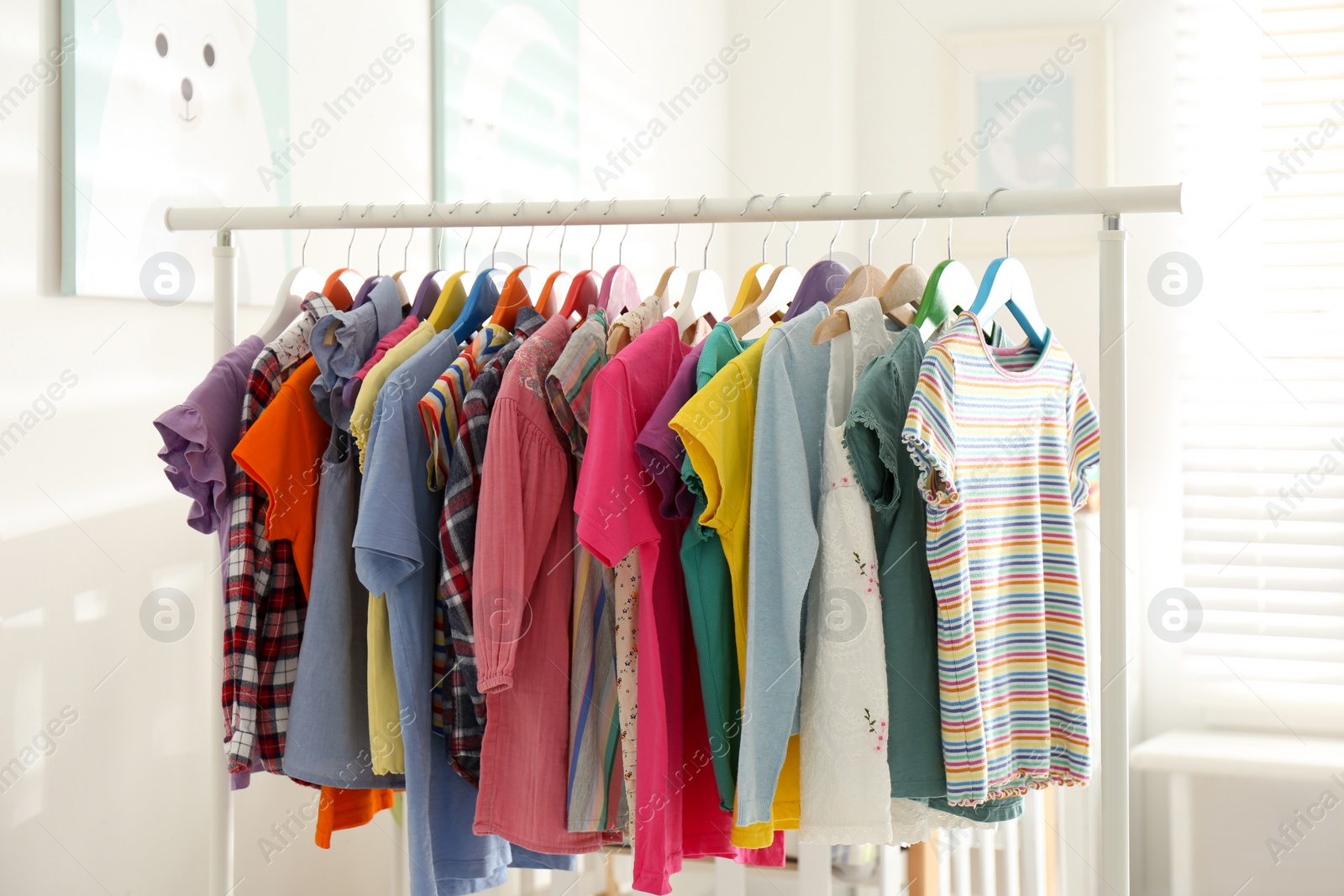 Photo of Different child's clothes hanging on rack in room