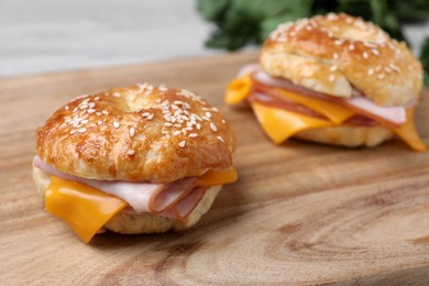 Photo of Delicious bagels with ham and cheese on wooden table, closeup. Space for text