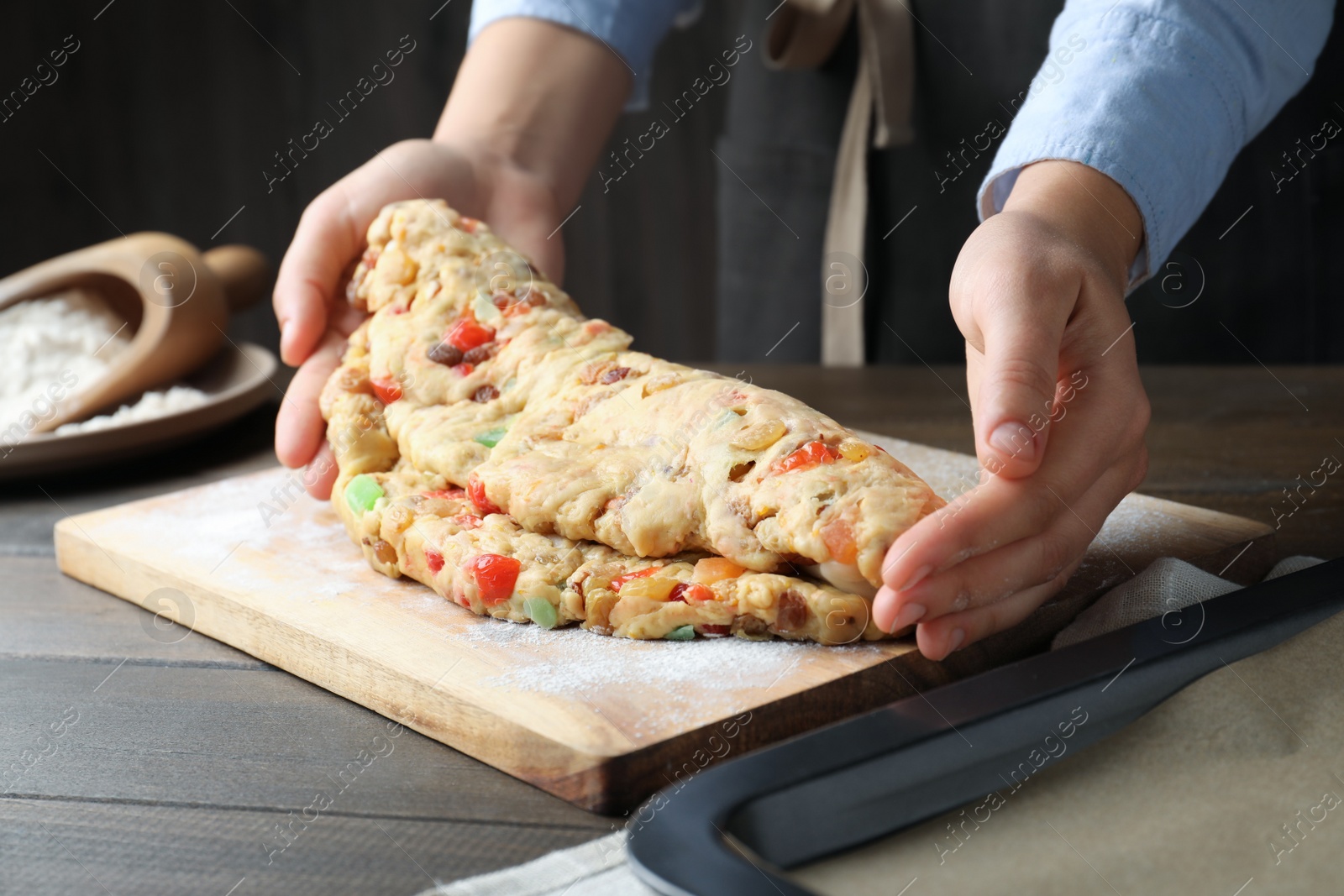 Photo of Woman making Stollen with candied fruits and raisins on wooden board at table, closeup