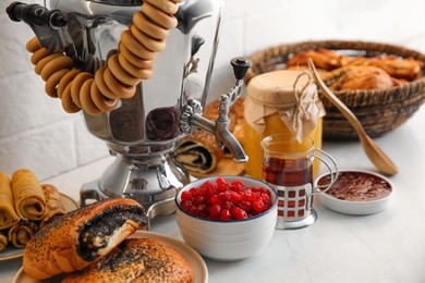 Photo of Traditional Russian samovar and treats on white table