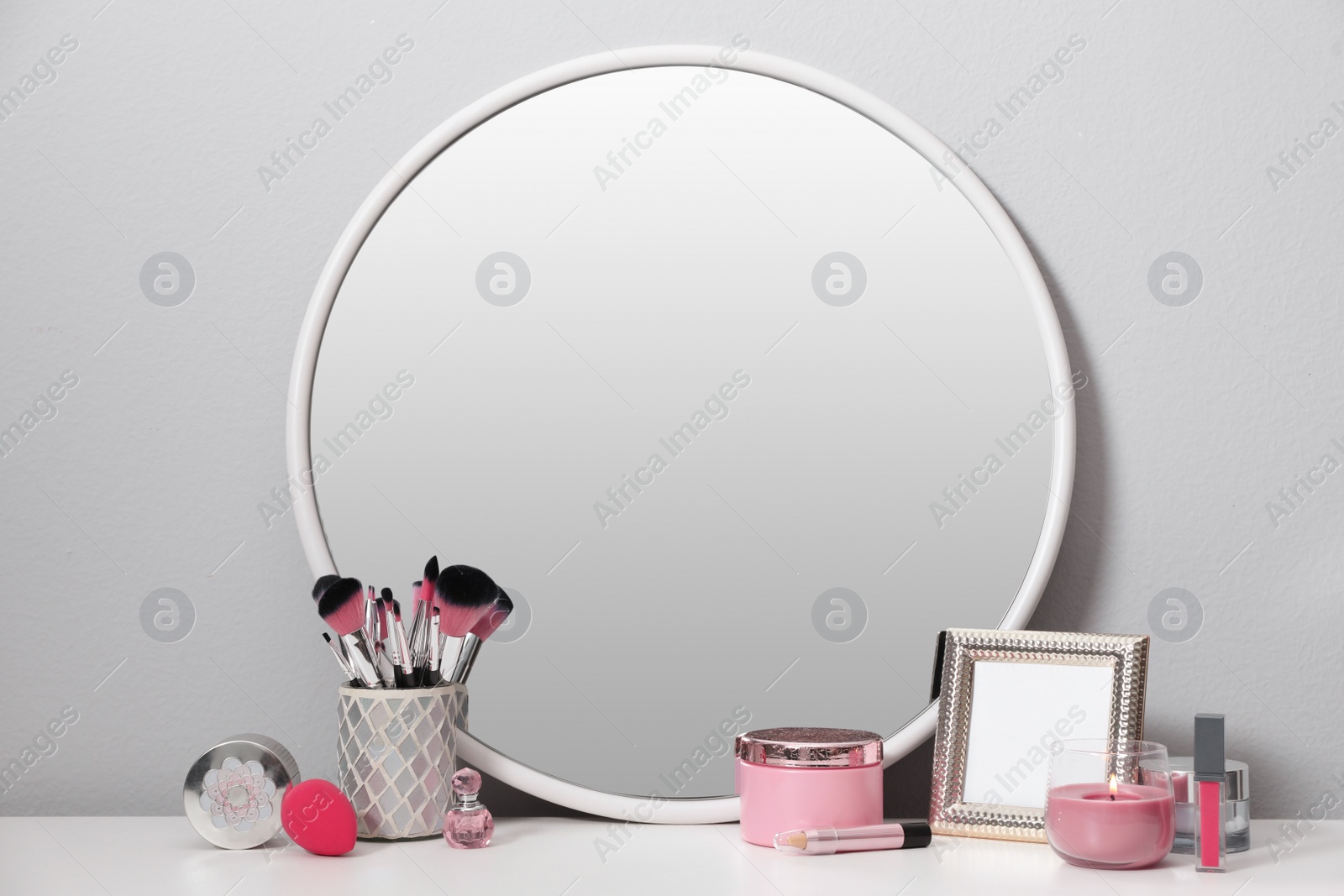 Photo of Stylish round mirror on dressing table with cosmetic products