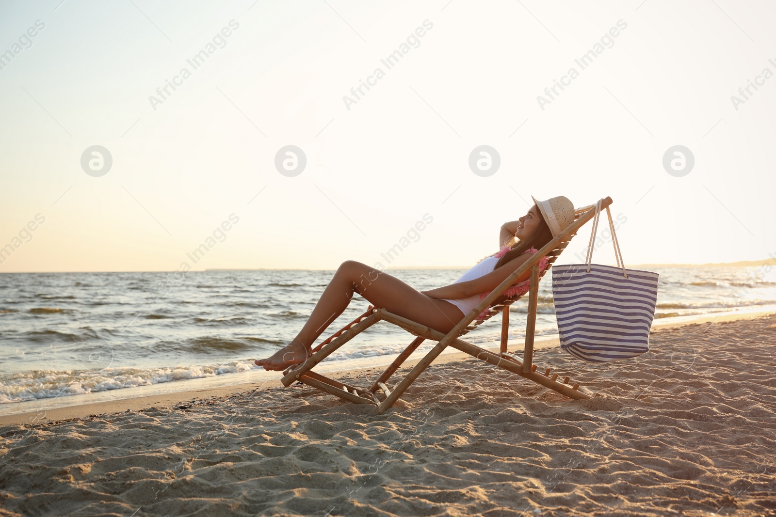 Photo of Young woman relaxing in deck chair on beach