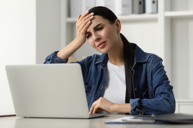 Photo of Woman suffering from headache at workplace in office