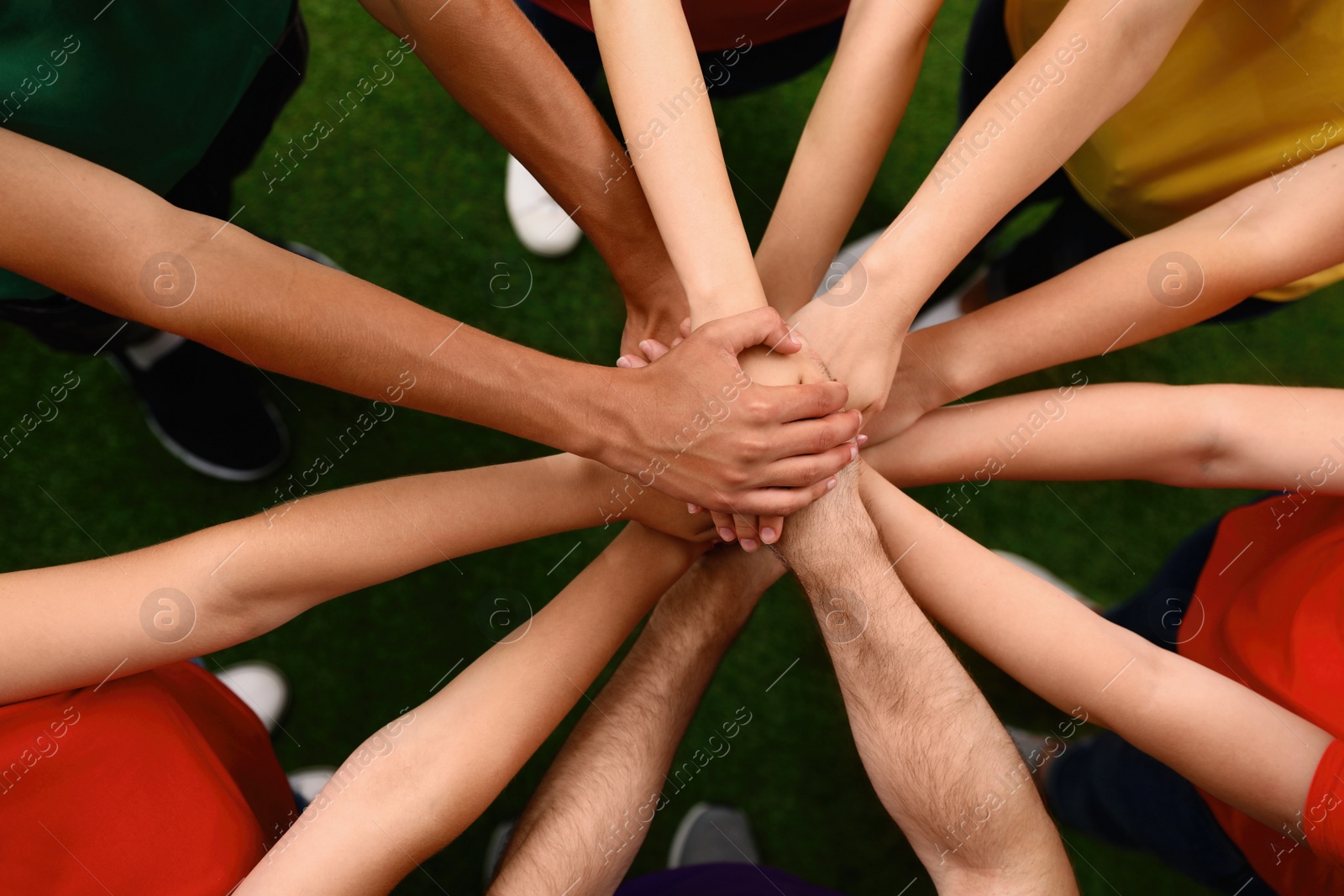 Photo of Group of volunteers joining hands together outdoors, top view