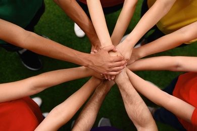 Photo of Group of volunteers joining hands together outdoors, top view