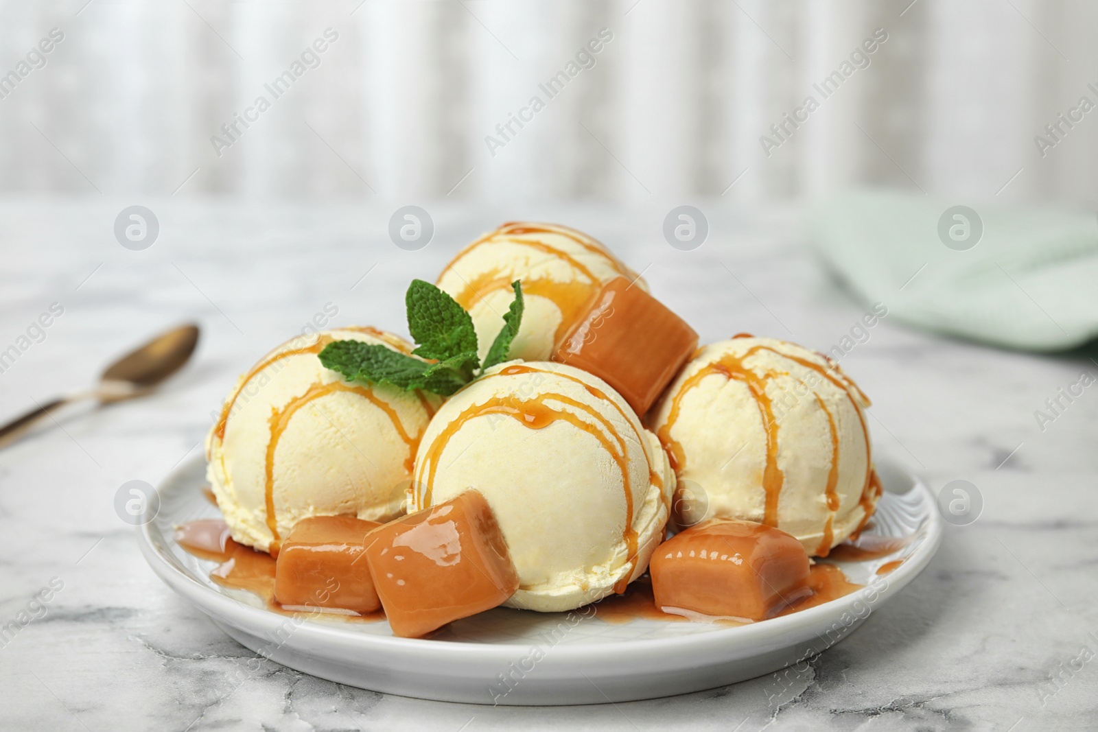 Photo of Delicious ice cream served with caramel and sauce on marble table
