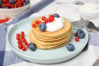 Tasty pancakes with natural yogurt, blueberries and red currants on table