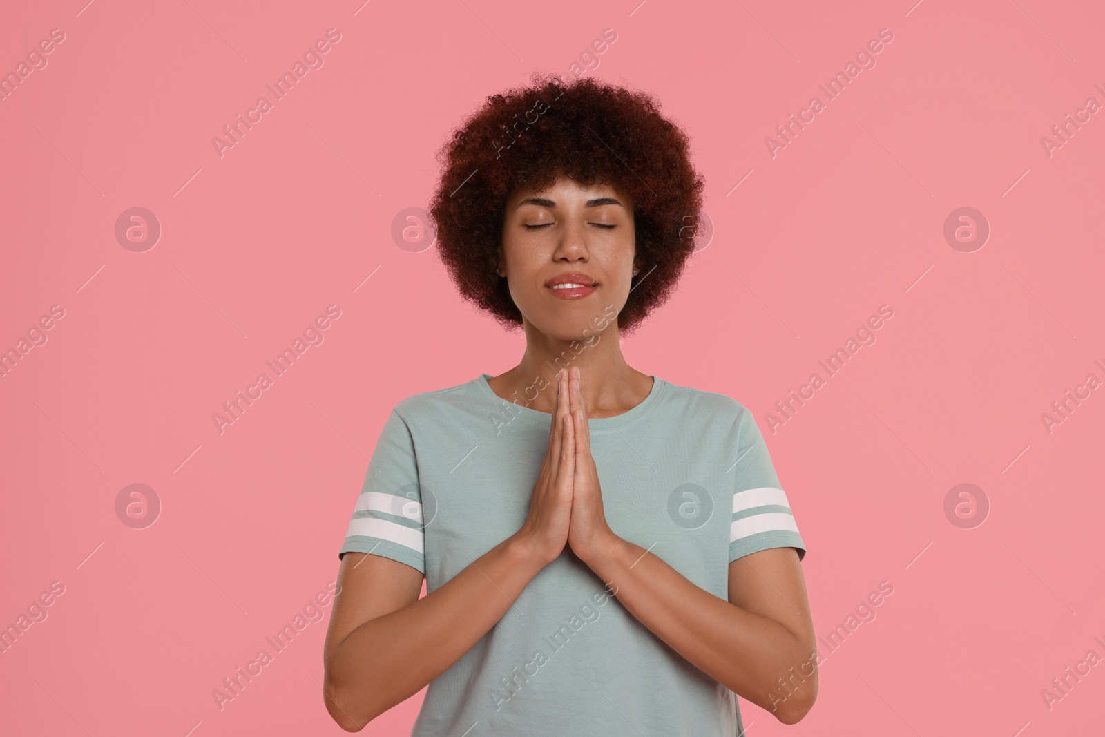 Photo of Woman with clasped hands praying to God on pink background