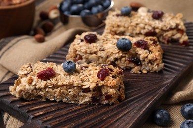 Photo of Tasty granola bars with berries on table, closeup