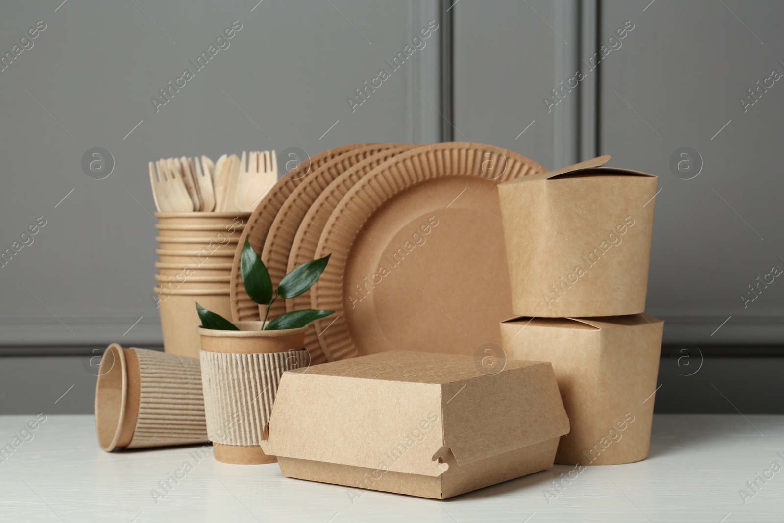 Photo of Disposable eco friendly products on white wooden table