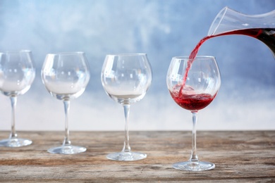 Photo of Pouring delicious red wine into glass on table