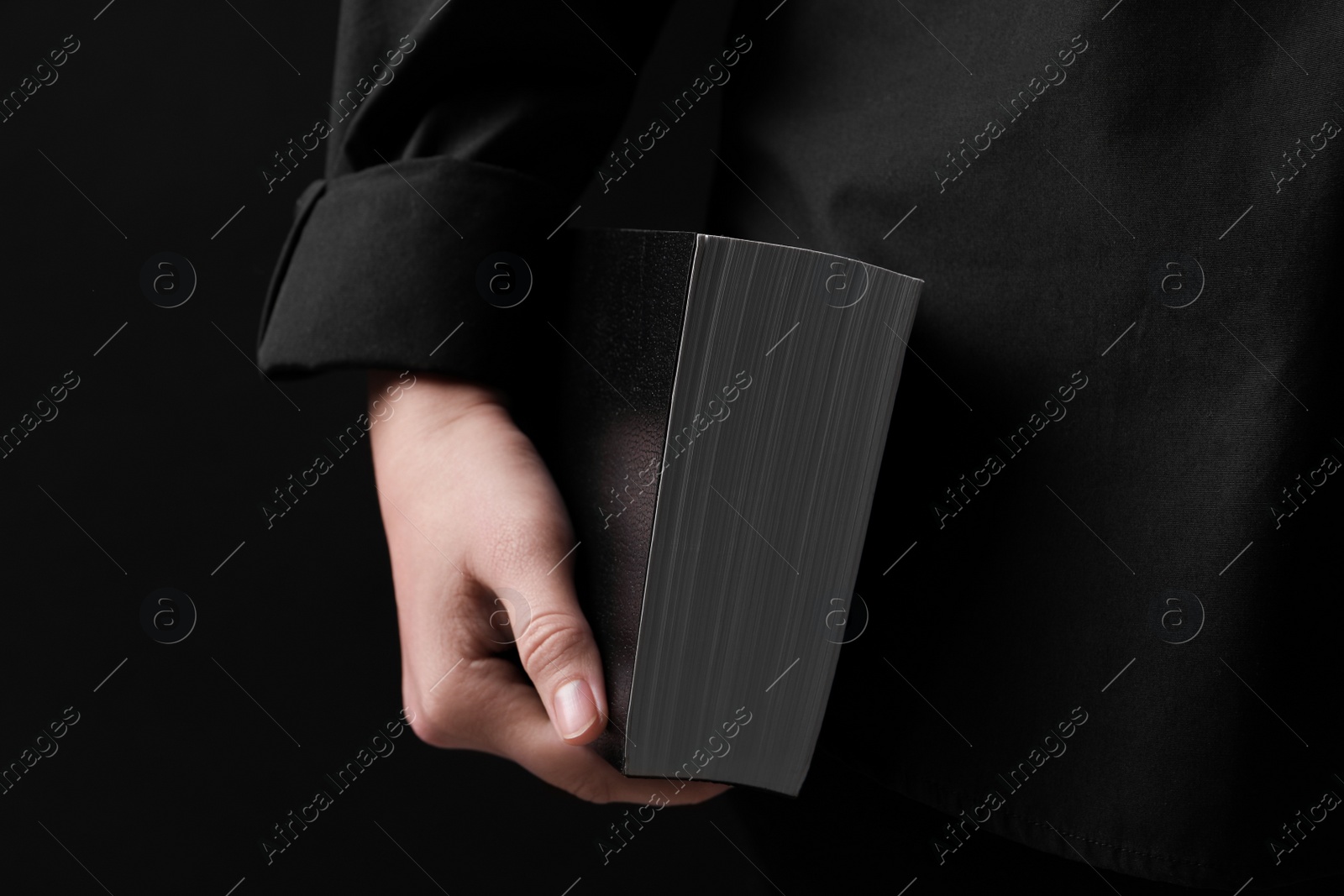 Photo of Woman with holy Bible on black background, closeup