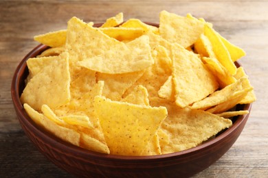 Photo of Bowl with tasty tortilla chips (nachos) on wooden table