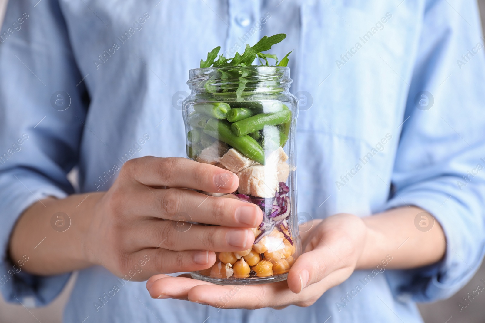 Photo of Woman holding glass jar with healthy meal, closeup