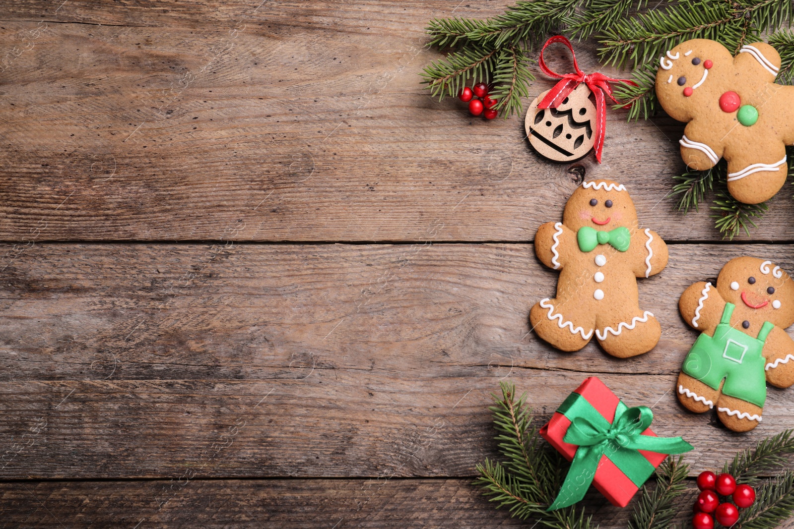 Photo of Flat lay composition with gingerbread men on wooden table, space for text