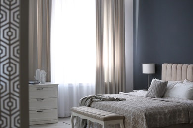 Photo of Beautiful curtains on window in stylish bedroom interior